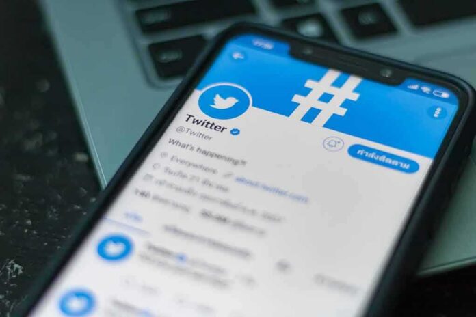 shutterstock_1239133447 Smartphone displaying Twitter app on a laptop keyboard