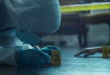 forensic investigator in protective suit examining crime scene markers