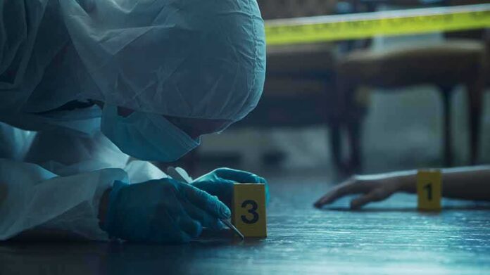 forensic investigator in protective suit examining crime scene markers