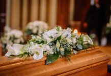 Mother Charged – Dad Can’t Bury 5-Year-Old Coffin with white floral arrangement