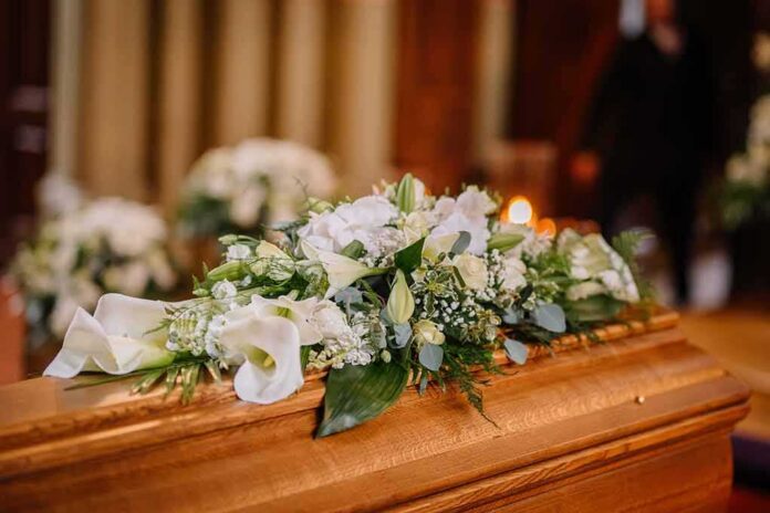 shutterstock_2288021055 Coffin with white floral arrangement