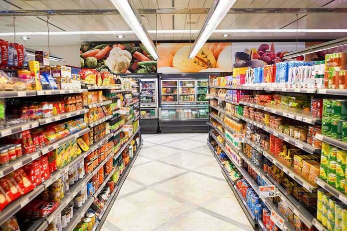 shutterstock_373602469 Grocery store aisle with stocked shelves and refrigerated section ahead