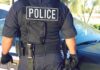 Police officer in tactical vest standing by patrol car