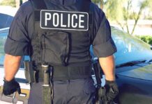 Police officer in tactical vest standing by patrol car